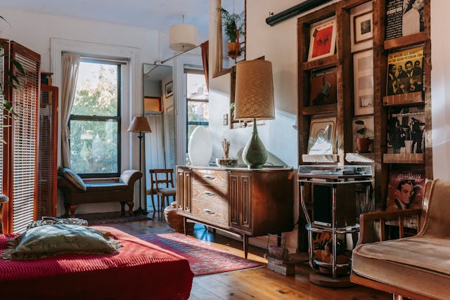 A room with tall shelves and an ottoman by the window 