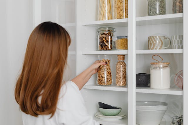 A woman putting a glass jar on a shelf