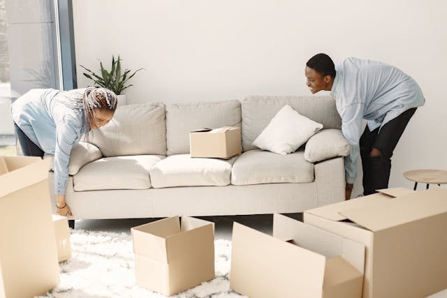 A man and a woman lifting a sofa together 
